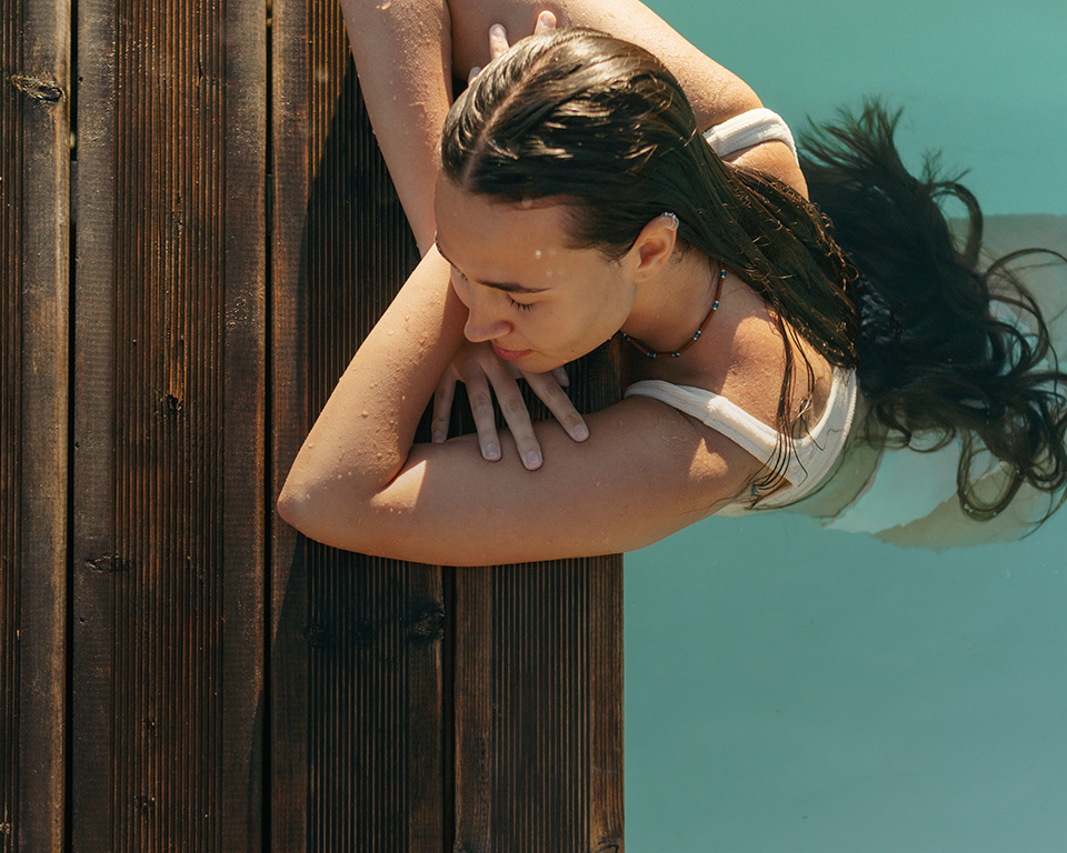 Frau im Pool, genießt das Wasser und die warme Sonne.