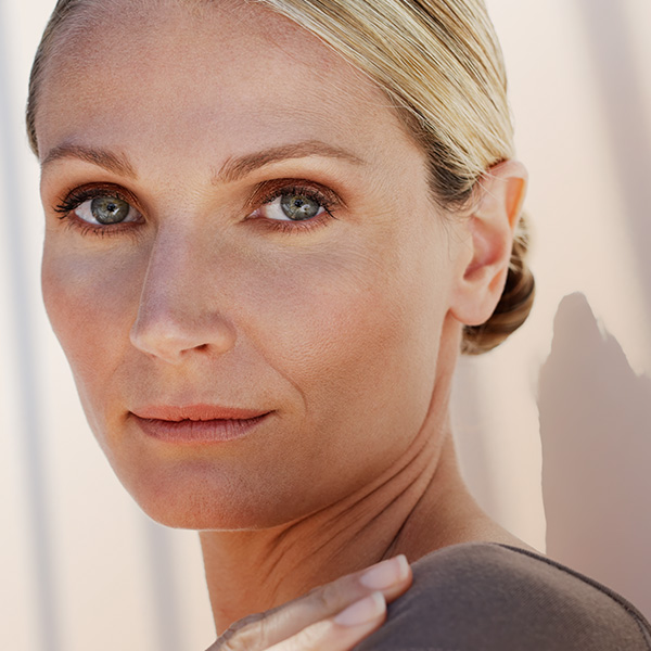 Blonde Frau blickt über ihre Schulter direkt in die Kamera