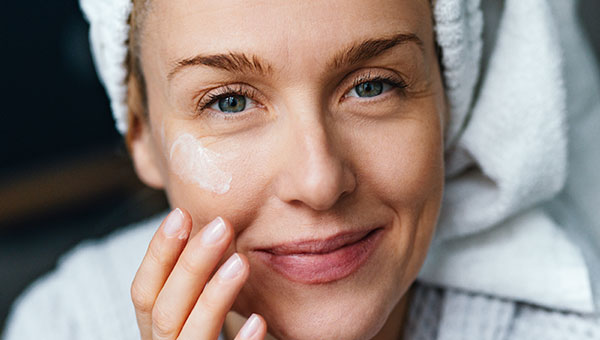 Close-Up einer Frau, die ihre Wange eincremt