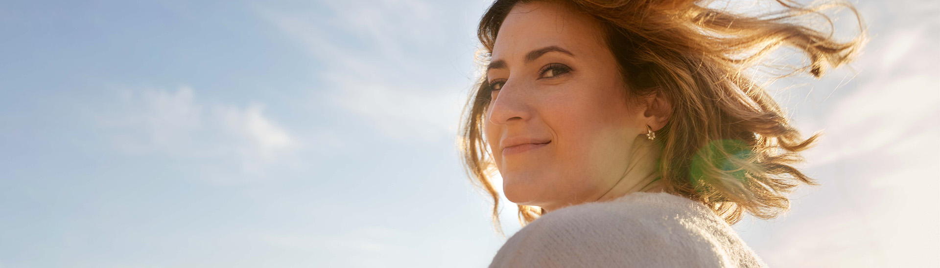 Frau vor blauen Himmel mit wehenden Haaren