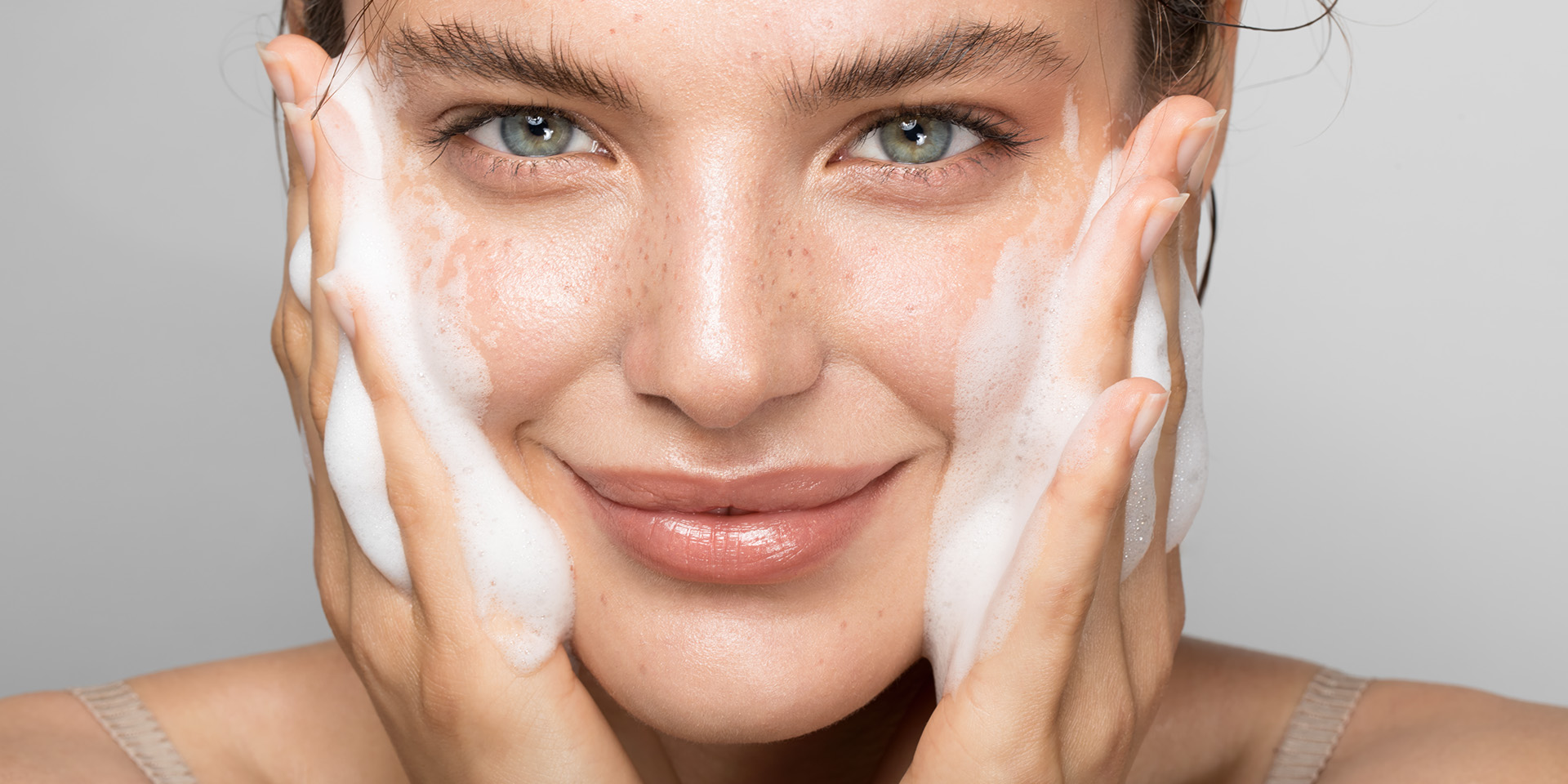 Frau reinigt ihr Gesicht mit Schaum