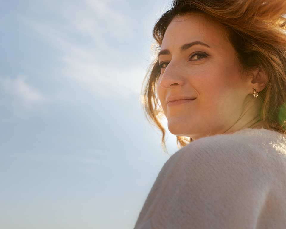 Frau vor blauen Himmel mit wehenden Haaren