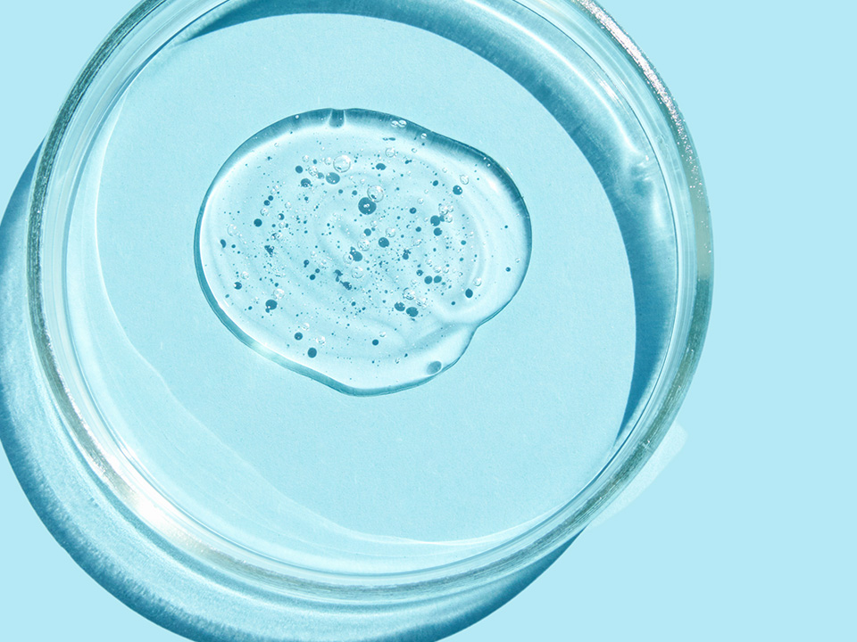 Eine Petrischale mit Hyaluronsaeure auf blauen Hintergrund