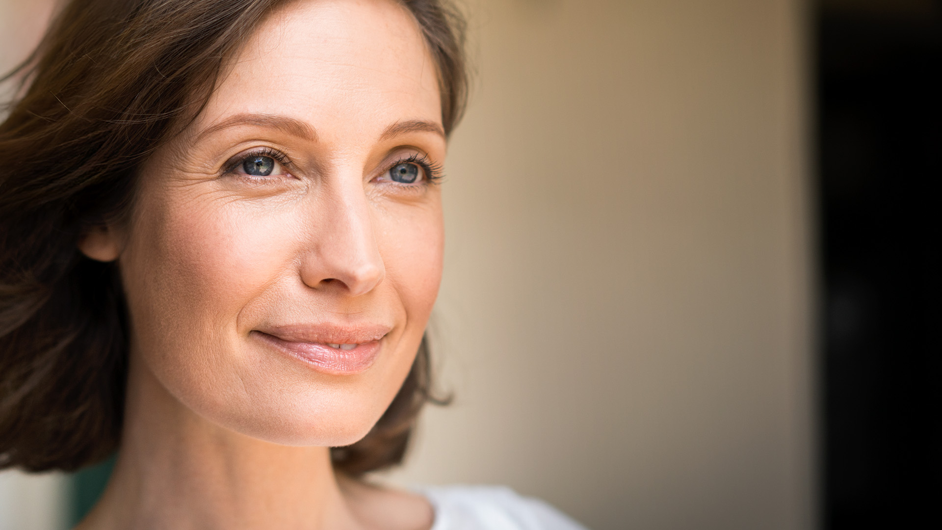 Frau mit wehenden Haaren blickt lächelnd in die Ferne